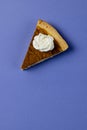 Composition of piece of pumpkin pie with whipped cream on blue background