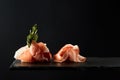 Composition of pieces of prosciutto or ham snack on black background Royalty Free Stock Photo