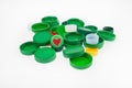 Composition with plastic bottle caps, one cap with heart image isolated on white. Recycling collection plastic caps. Royalty Free Stock Photo