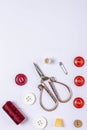 A composition of red sewing thread, thimble, vintage scissors, buttons and safety pin on a white background Royalty Free Stock Photo