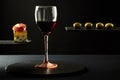 Composition of red wine in glass and pieces of prosciutto and cheese and olives on black background Royalty Free Stock Photo