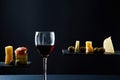 Composition of red wine in glass and pieces of prosciutto and cheese and olives on black background Royalty Free Stock Photo