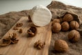 Composition of a round cheese head with white mold and walnuts on a bamboo board on a background of burlap Royalty Free Stock Photo