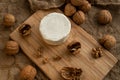 Composition of a round cheese head with white mold and walnuts on a bamboo board on a background of burlap Royalty Free Stock Photo