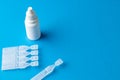 Composition of saline solution caplets and dropper bottle on blue background with copy space
