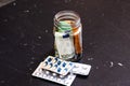 Composition with saving money banknotes in a glass jar with pills. Concept of investing and keeping money for healthcare, close up Royalty Free Stock Photo