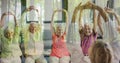 Composition of senior group practicing yoga with instructor and trees in sunlight