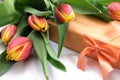 Several orange yellow tulips and a gift box