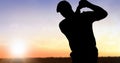 Composition of silhouette of golf player over landscape and sun on blue sky with copy space