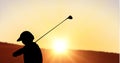 Composition of silhouette of golf player over landscape and sun setting with copy space