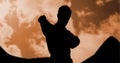 Composition of silhouette of male martial artist against orange sky with sun setting Royalty Free Stock Photo