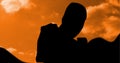 Composition of silhouette of male martial artist over orange sky with sun setting Royalty Free Stock Photo