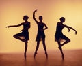 Composition from silhouettes of three young dancers in ballet poses on a orange background. Royalty Free Stock Photo