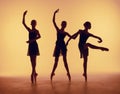 Composition from silhouettes of three young dancers in ballet poses on a orange background. Royalty Free Stock Photo