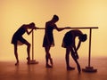 Composition from silhouettes of three young dancers in ballet poses on a orange background. Royalty Free Stock Photo