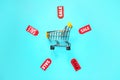 Composition with small shopping cart and tags on color background Royalty Free Stock Photo