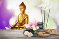 Composition with smoldering incense sticks on wooden table and Buddha figure on background. Space for text