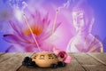 Composition with smoldering incense sticks on wooden table and Buddha figure on background