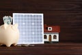 Composition with solar panel and piggy bank on table
