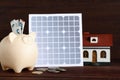 Composition with solar panel and piggy bank on table