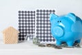 Composition with solar panels and piggy bank on wooden table