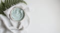 A composition of spa essentials with a towel, cosmetic clay, and a fern leaf displayed on a white background, showcasing Royalty Free Stock Photo