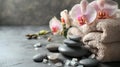 Composition of spa settings with orchid on gray background, spa stones, towels and orchid on grey Royalty Free Stock Photo