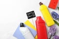 Composition with Spring Cleaning sign, flowers and detergents on white background, top view