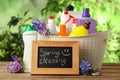 Composition with Spring Cleaning sign, flowers and detergents on wooden table