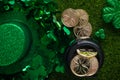 Composition for St. Patrick`s Day with shiny hat of leprechaun with clover and coins on green grass background. Flat lay. View Royalty Free Stock Photo