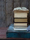 The composition of a stack of old books and glasses on a wooden background. Vintage photo. Side view. Royalty Free Stock Photo