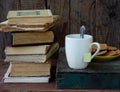 The composition of a stack of old books, tea cups, glasses and plates of sugar cookies on a wooden background. Vintage photo. Side Royalty Free Stock Photo