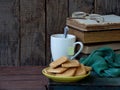 The composition of a stack of old books, tea cups, glasses and plates of sugar cookies on a wooden background. Vintage photo. Side Royalty Free Stock Photo