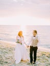 The composition of the sunset in the sea. The newlyweds are holding hands during their walk. Royalty Free Stock Photo