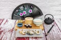 Composition of sushi plates with teapot, painted fan, white rice, soy sauce, chopsticks, ginger and wasabi, dim sum, red wooden Royalty Free Stock Photo