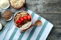 Composition with tasty oatmeal and different toppings on wooden table