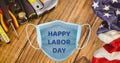 Composition Of Text Happy Labor Day On Face Mask With Tools And American Flag On Wood Background