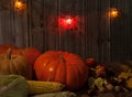 Pumpkin, corn cob, apples, autumn leaves, walnuts and chestnuts, colorful lanterns on a wooden background. Royalty Free Stock Photo