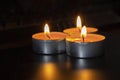 Composition of three candles on dark luxury night background. Black table, side view. Candles Burning at Night. Orange taper Royalty Free Stock Photo