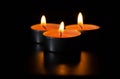 Composition of three candles on dark luxury night background. Black table, side view. Candles Burning at Night. Orange taper Royalty Free Stock Photo