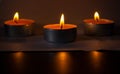 Composition of three candles on dark luxury night background. Black table, side view. Candles Burning at Night. Orange taper Royalty Free Stock Photo