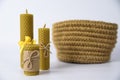 A composition of three candles made of wax and a knitted basket made of jute on a white background Royalty Free Stock Photo