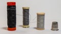 Composition of three spools of sewing thread tied together like a hug and a dressmaker`s thimble Royalty Free Stock Photo