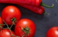 Composition of tomato bunch and hot pepper on black piece of board, top view, close-up. Royalty Free Stock Photo