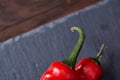 Composition of tomato bunch and hot pepper on black piece of board, top view, close-up. Royalty Free Stock Photo