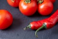 Composition of tomato bunch and hot pepper on black piece of board, top view, close-up. Royalty Free Stock Photo