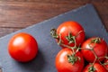 Composition of tomato bunch and hot pepper on black piece of board, top view, close-up. Royalty Free Stock Photo