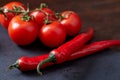 Composition of tomato bunch and hot pepper on black piece of board, top view, close-up. Royalty Free Stock Photo