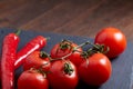 Composition of tomato bunch and hot pepper on black piece of board, top view, close-up. Royalty Free Stock Photo