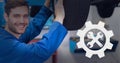 Composition of tools and cog icon over smiling caucasian car mechanic fixing car Royalty Free Stock Photo